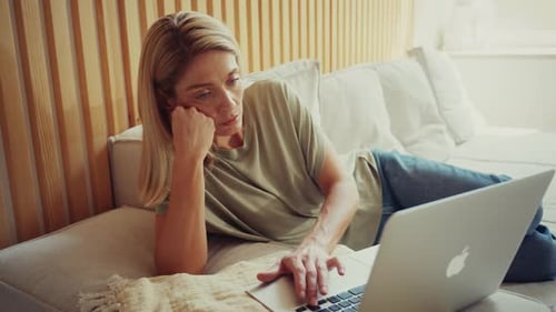 Unhappy Woman Using Laptop While Sitting on Sofa