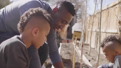 Father and sons enjoy gardening together in their Canada backyard in springtime