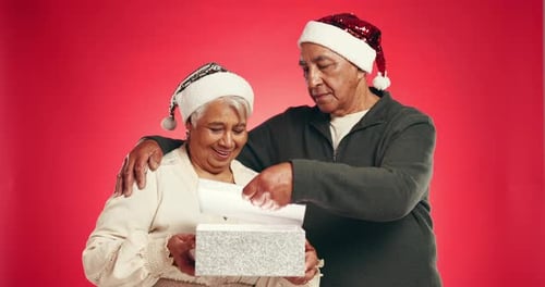 Christmas, gift and surprise with old couple in studio for love, holiday season