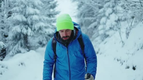 Handsome Young Man Walk Alone in the Winter Mountains in Forest Road with Trekking Poles Sport