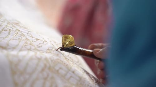 The technique of making hand-drawn batik using a canting tool. This craftsman is making batik typica