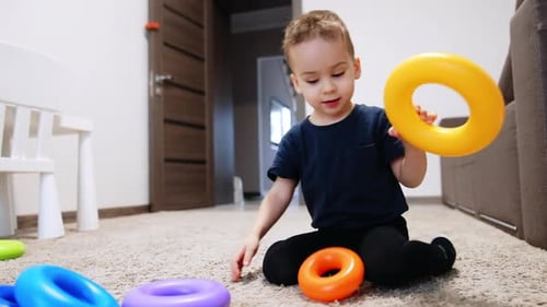 Little Boy Playing with Colorful Stacking Rings at Home