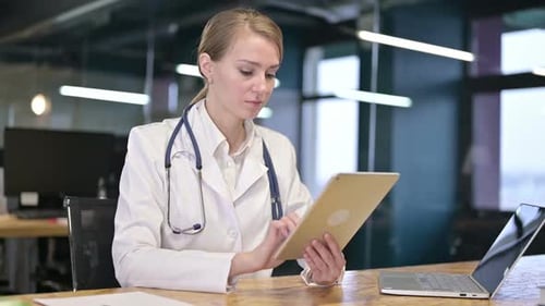Hardworking Young Female Doctor using Tablet in Office