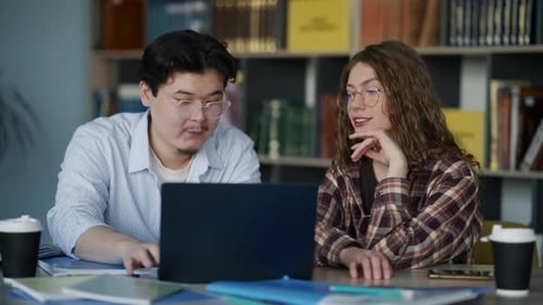 Studierende arbeiten in der Universitätsbibliothek am Laptop zusammen