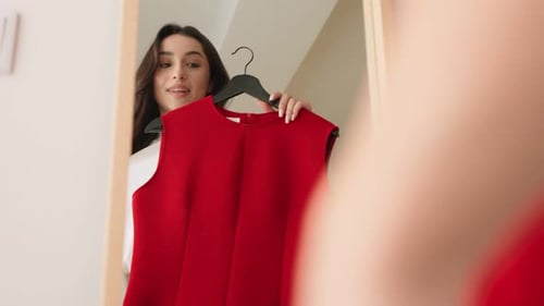 Mulher elegante experimentando um vestido vermelho no espelho