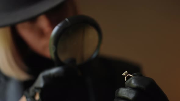 Female Detective Examines Diamond Ring with Magnifying Glass During ...