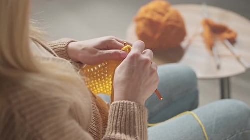 Woman Crocheting with Yellow Yarn in Cozy Home