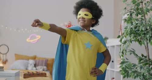 Slow Motion Portrait of Adorable African American Kid in Superhero Costume Cape and Mask Standing at