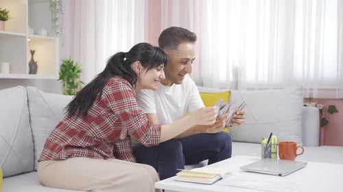The couple counting money at home rejoices. High income couple.