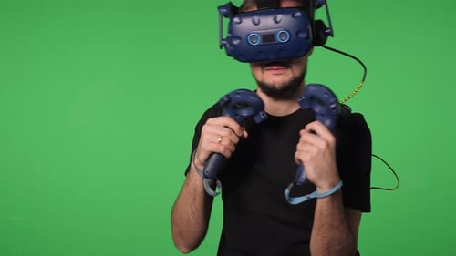 A Man Uses Virtual Reality Glasses to Play in a Studio on a Green Background