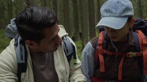 Male Hiker Checking Injured Leg of Girlfriend Sitting on Fallen Log in Forest