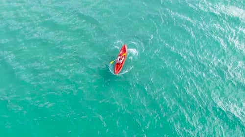 A man doing kayaking in crystal blue water, from above.