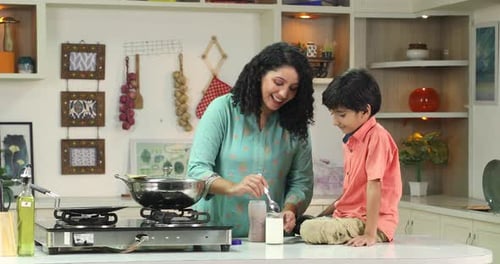 Woman Pours Milk for Child in Kitchen