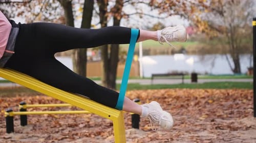 Woman Exercising Legs With Resistance Band in Park