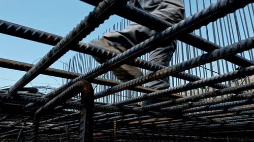 Construction Workers Navigating a Steel Rebar Grid at a Building Site