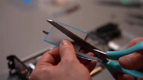 Hands Cutting Plastic with Scissors Close Up