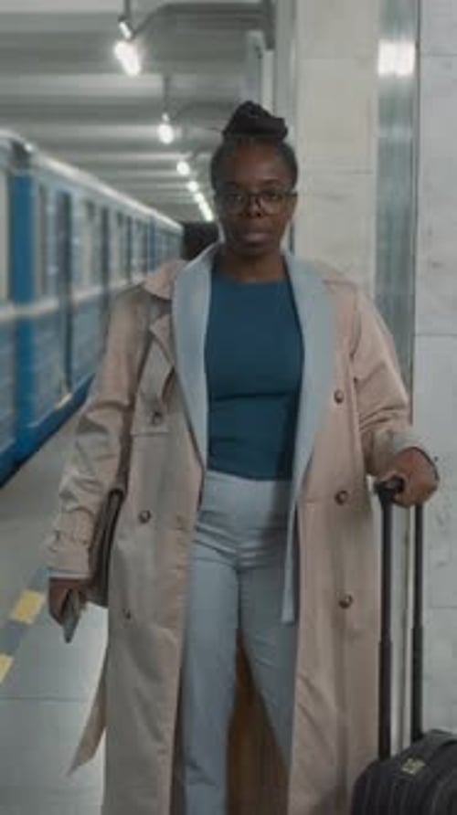 Vertical Portrait of Black Traveler with Luggage by Passing Metro Train