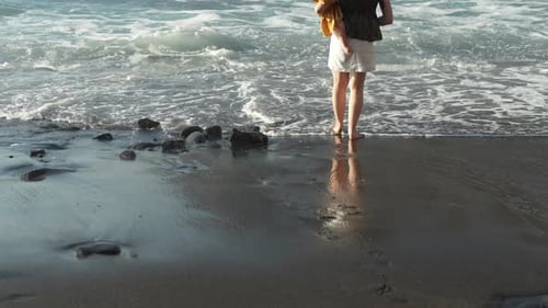 Mother Carries Baby Along Beach. Feet in Ocean Waves, Slowmo