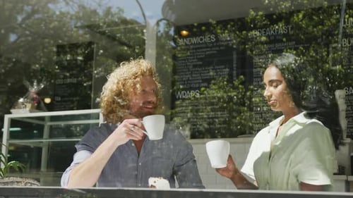 Happy diverse couple drinking coffee and talking in cafe