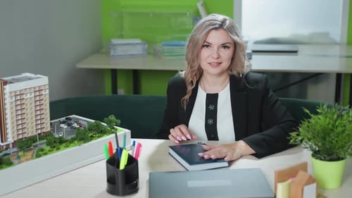 Professional Woman Smiling While Closing Book in Office Setting