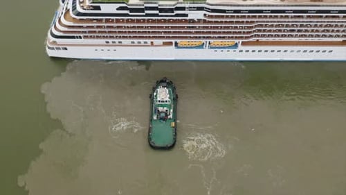 Tug boat assisting cruise ship arrival to port. Bottom sediment mixed by vessel propulsion. High alt
