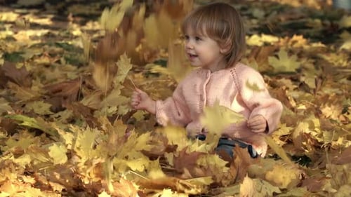 Girl Plays with Leaves in Autumn Park