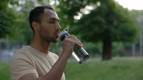 Side View of African American Man is Drinking Water From the Sport Bottle