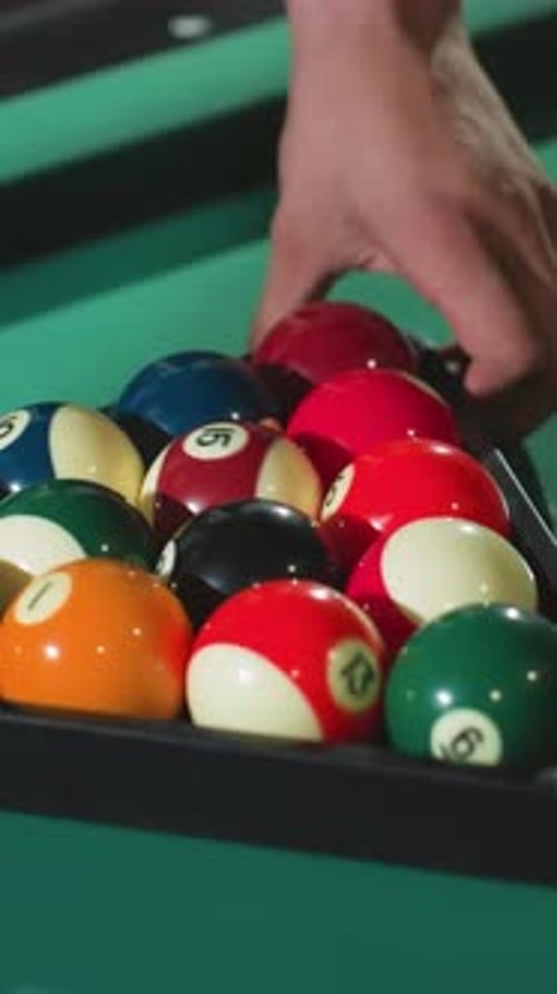 CloseUp of Hand Rolling Billiard Balls in Triangle Rack on Green Pool Table