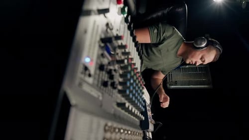 A close-up of a mixing console device used by a man working as professional sound engineer in studio