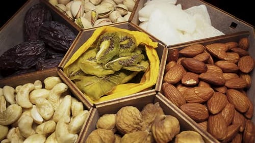 A set of dried fruits and nuts in a wooden box. Rotate close-up.