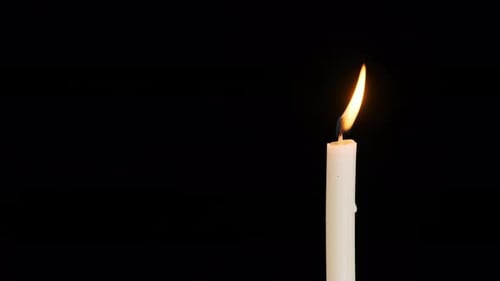 One Candle Burning and Extinguished on a Black Background Copy Space