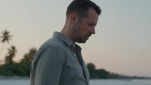 Parallax shot of thoughtful man standing in silence on the beach contemplating about life and past d