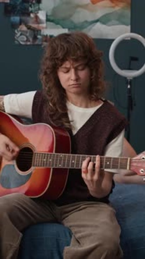 Woman Plays Guitar for Friend in Bedroom