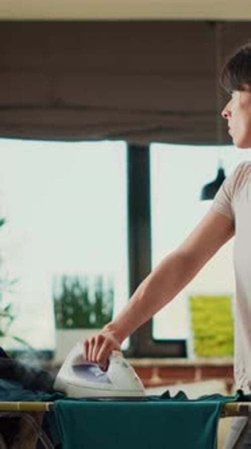 Woman Ironing Clothes While Man Talks on Phone