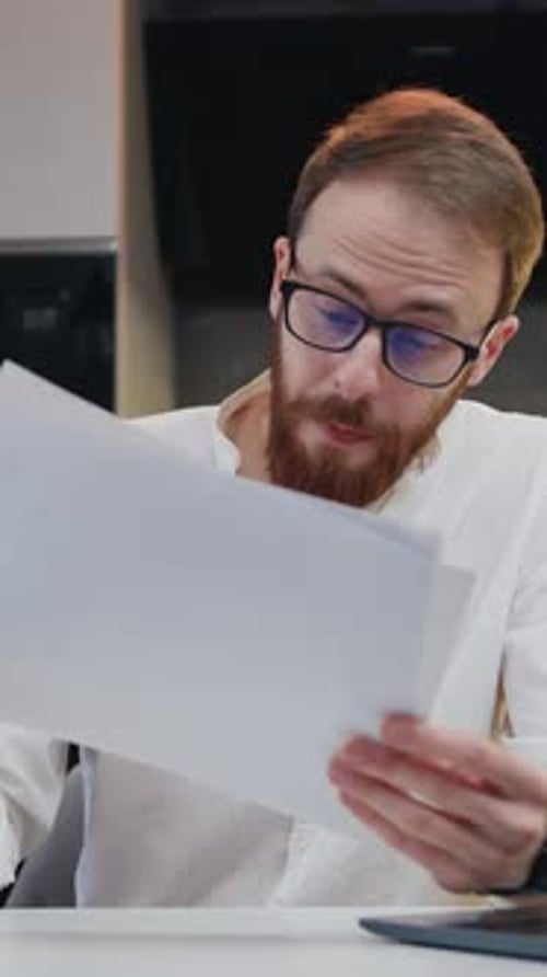 Man Reviews Documents During Video Call From Home