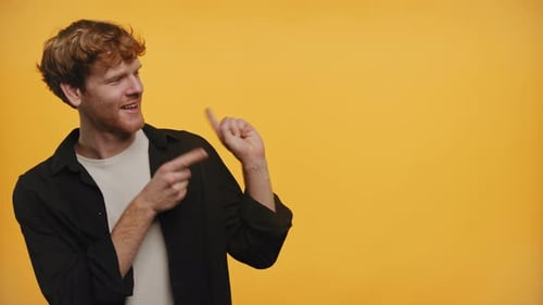 Man Smiling and Pointing Sideways on a Yellow Background