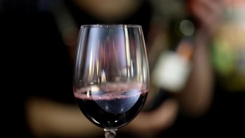 Barkeeper gießt Rotwein im Restaurant ein, Nahaufnahme von Glas auf der Bartheke, Abend in der Bar