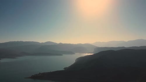 Aerial drone flying over a lake, water dam, with mountains at sunrise. Beautifull dreamy landscape.