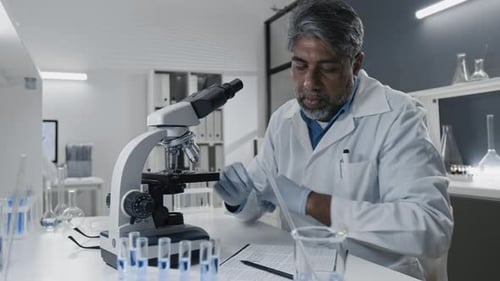 Researcher Studying Sample under Microscope