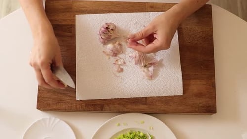 In this close-up video, a woman skillfully shaves garlic with a knife