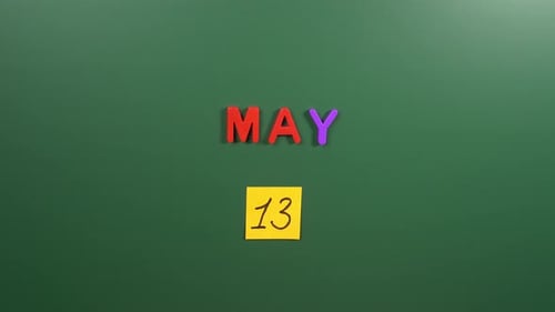 Hand sticking a sticker 13 May calendar day on school board. 13 date of May. Thirteenth day May