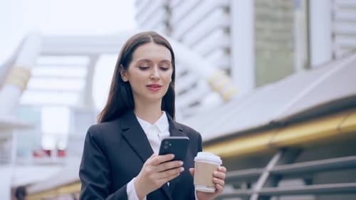 Caucasian young businesswoman talking on smartphone while walk in city. Attractive beautiful female