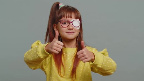 Child Smiling With Eye Patch Gives Thumbs Up