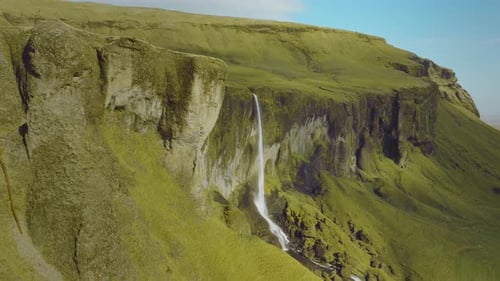 Scenic Waterfall Cascading Down Green Cliffside Mountain