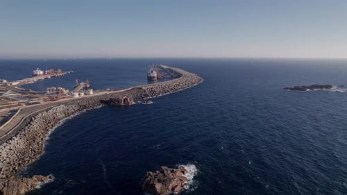 Quebra-mar curvo do Porto de Sines que se estende até o Oceano Atlântico no miradouro da Costa Norte, Alentejo