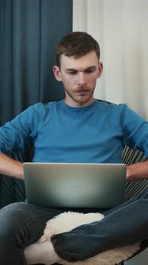 Young Man Sits and Works On Laptop