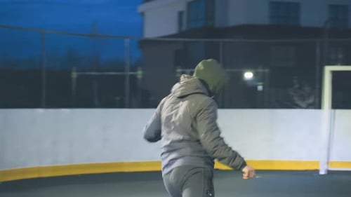 Man Kicks Soccer Ball on Urban Field at Night