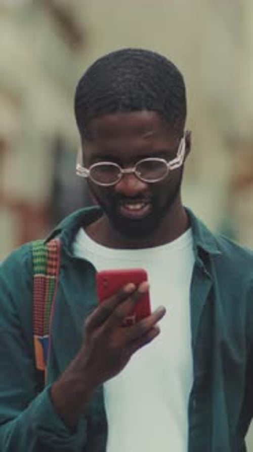 Young Man with Glasses Using a Smartphone