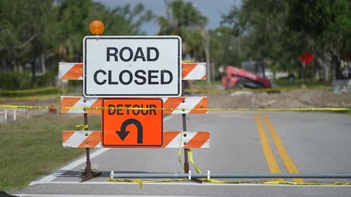 Warning Roadworks Sign and Safety Barrier on City Street During Maintenance Repair Work