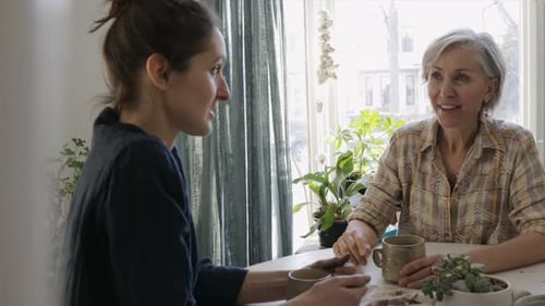 Madre e hija maduras disfrutando del té y conversando juntas en casa